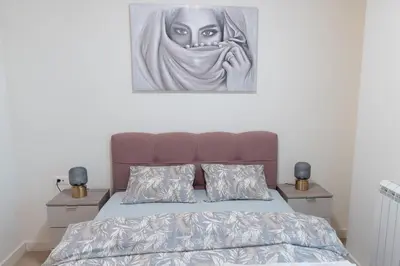 a painting of a woman is hanging above a bed at Tommy BW in Belgrade