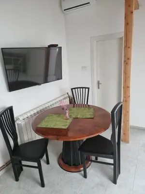 a dining room table with chairs and a television on a wall at HEART OF BELGRADE cozy LUX APARTMENT in Belgrade