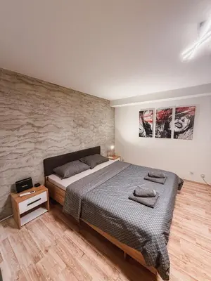 a bedroom with a bed and a stone wall at Mateja Apartman in Belgrade
