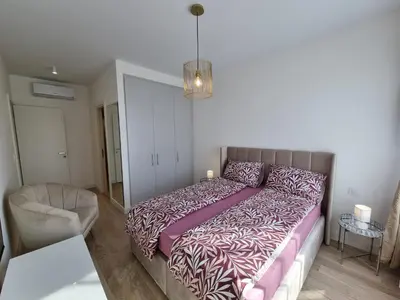 a bedroom with a large bed and a chair at BW Aria deluxe apartments in Belgrade