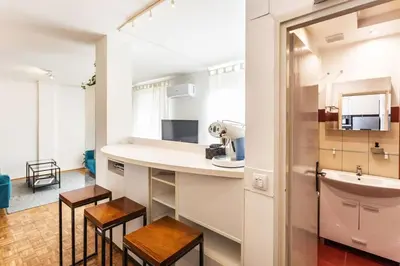 a kitchen with a sink and a counter with stools at Lovely Studio with a big terrace in Belgrade