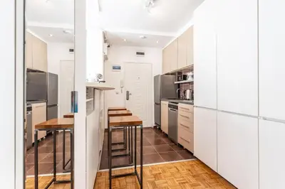 a kitchen with white cabinets and a wooden floor at Lovely Studio with a big terrace in Belgrade
