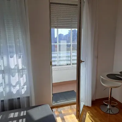 a bedroom with a large glass door with a window at Manhattan apartman Zumbul Belvil in Belgrade