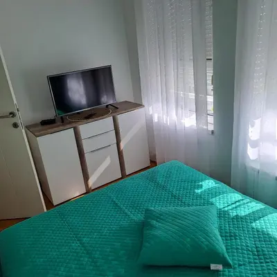 a bedroom with a bed with a green comforter and a television at Manhattan apartman Zumbul Belvil in Belgrade