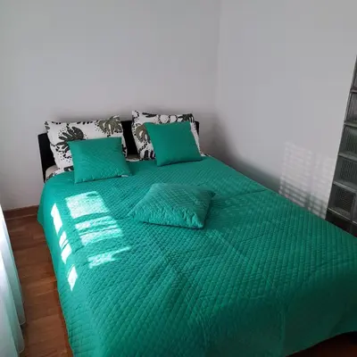 a green bed with green sheets and pillows at Manhattan apartman Zumbul Belvil in Belgrade