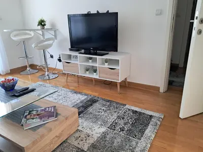 a living room with a television on a white cabinet at Manhattan apartman Zumbul Belvil in Belgrade
