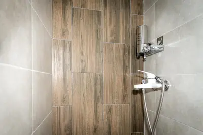 a bathroom with a shower with a wooden wall at Luxury Stay in Belgrade Waterfront with Views in Belgrade