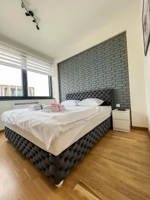 a large bed in a bedroom with a brick wall at Modern Luxury in Belgrade Waterfront with Views in Belgrade