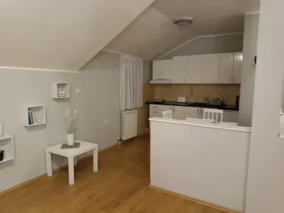 a kitchen with a white counter and a table at Apartman Mima in Borča