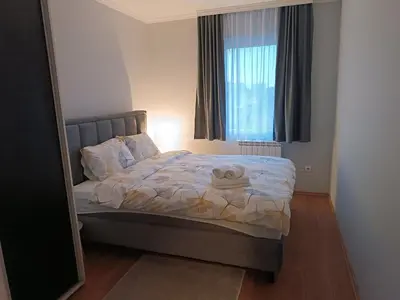 a bedroom with a bed with a window and a mirror at Apartman Mima in Borča