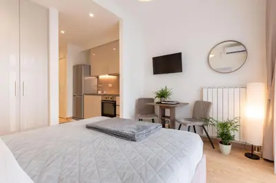 a bedroom with a white bed and a kitchen at Lovely Studio Apartment - Belgrade Waterfront - Free Parking in Belgrade