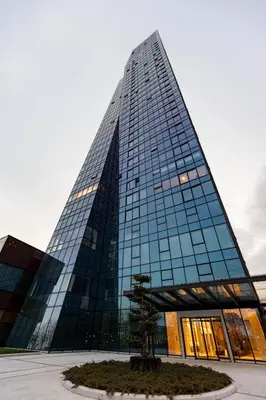 a tall building with a tree in front of it at In The Sky - Apartment West 65 Tower in Belgrade