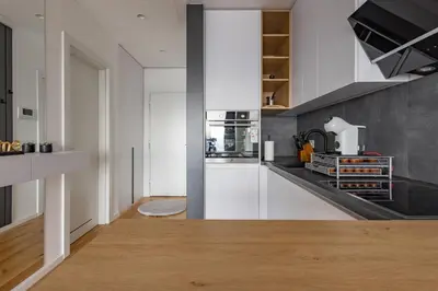 a kitchen with white cabinets and a wooden floor at In The Sky - Apartment West 65 Tower in Belgrade