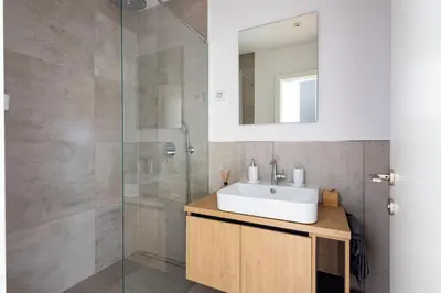 a bathroom with a sink and a glass shower at In The Sky - Apartment West 65 Tower in Belgrade
