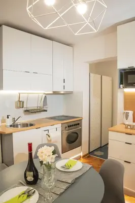 a kitchen with white cabinets and a table with flowers on it at Dorotea Lux in Belgrade