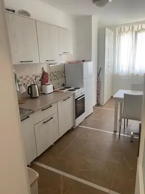 a kitchen with white cabinets and a table and a counter top at Apartment Bruno NICE PLACE in Belgrade