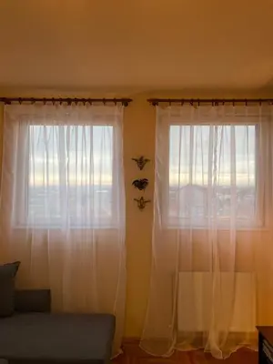 a living room with white curtains and a couch at Apartman Helena in Lazarevac
