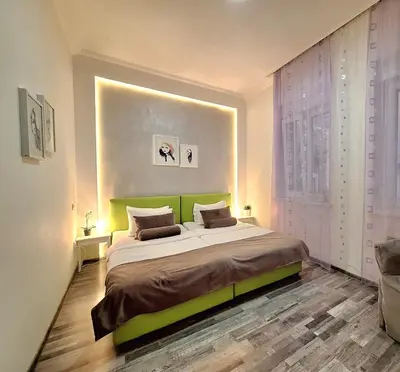 a bedroom with a large bed with a green headboard at GENIUS APARTMENT in Belgrade
