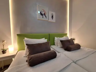 a bedroom with two beds and a green headboard at GENIUS APARTMENT in Belgrade