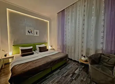 a bedroom with a large bed and a chair at GENIUS APARTMENT in Belgrade