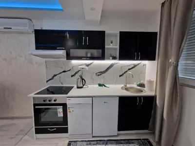 a kitchen with black and white cabinets and a sink at AT Mirror in Voždovac