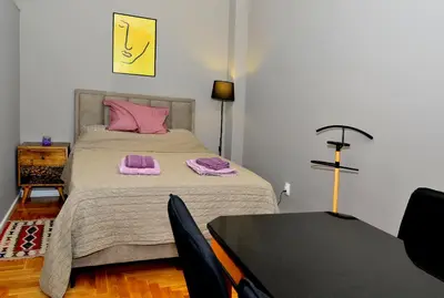 a bedroom with a bed with pink pillows and a table at Kursula in Vračar (historical)