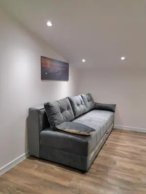 a grey leather couch in a room with a wall at SAMITEST in Batajnica