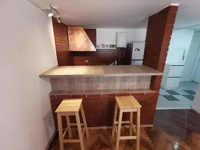 a kitchen with two stools and a brick wall at Nov apartman u mirnoj ulici u centru Beograda in Belgrade