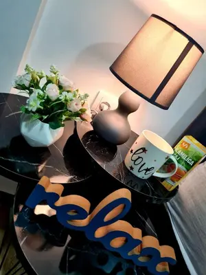 a table with a lamp and a vase with flowers on it at Stella Apartman Ruma in Ruma