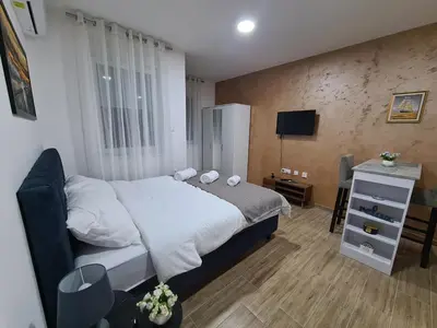 a bedroom with a large bed and a television at Stella Apartman Ruma in Ruma