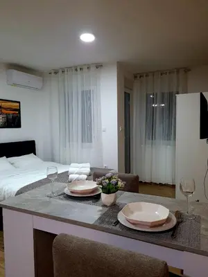 a room with a bed and a table with plates and wine glasses at Stella Apartman Ruma in Ruma