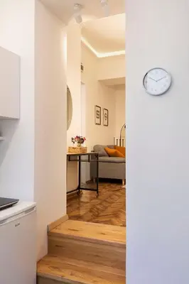 a kitchen and living room with a clock on the wall at High Note Apartment in Belgrade