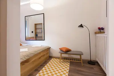 a bedroom with a bed and a mirror and a chair at High Note Apartment in Belgrade