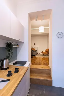 a kitchen with white cabinets and a staircase leading to a living room at High Note Apartment in Belgrade