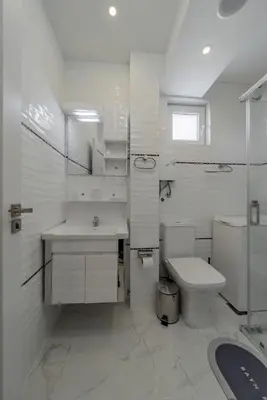 a white bathroom with a sink and a toilet at TIMS Apartman 7 in Belgrade