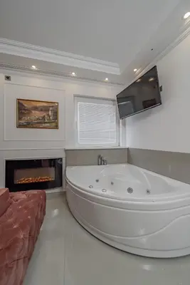 a large white bath tub in a room with a fireplace at TIMS Apartman 7 in Belgrade
