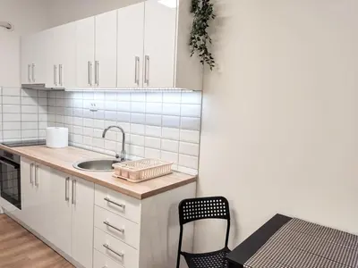 a kitchen with white cabinets and a sink and a chair at Zarkovo in Belgrade