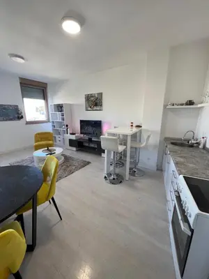 a kitchen and living room with a table and yellow chairs at Belgrade Center Apartment Lux IV in Belgrade