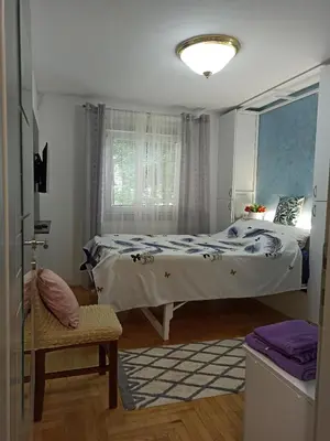 a bedroom with two beds and a chair and a window at Santa Barbara Apartment in Belgrade