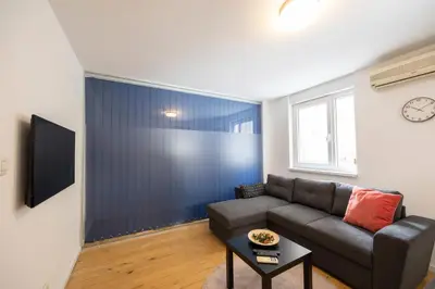 a living room with a couch and a clock on a wall at Belgrade Center Apartment Skadarlija III in Belgrade