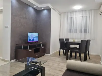 a living room with a table and chairs and a television at stan Slavija in Sajmište