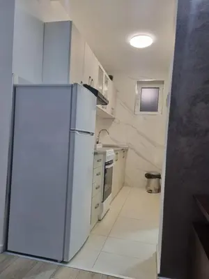 a kitchen with a white refrigerator in a room at stan Slavija in Sajmište