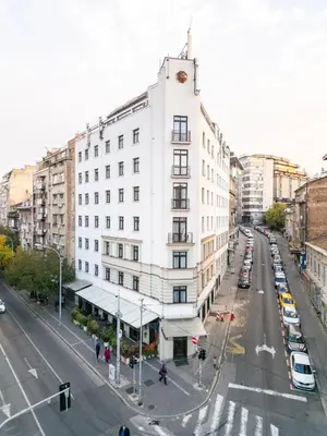 a tall white building on a city street with cars at Kopernikus Hotel Prag in Belgrade