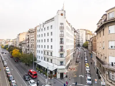 a tall white building on a city street with cars at Kopernikus Hotel Prag in Belgrade
