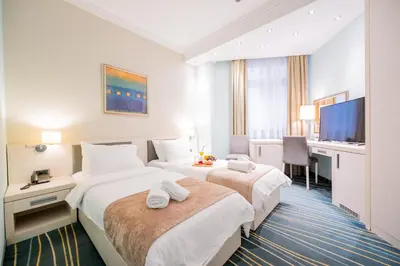 a hotel room with two beds and a flat screen tv at Kopernikus Hotel Prag in Belgrade
