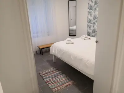 a bedroom with a white bed and a mirror at Bibi Zahumska apartman in Belgrade