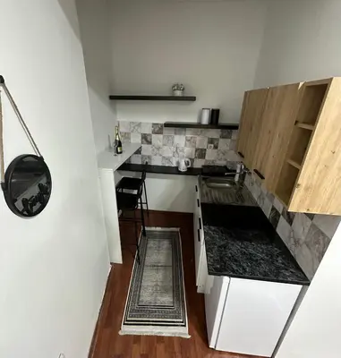 a small kitchen with white counters and wooden cabinets at Central Peaceful Nest Belgrade in Belgrade