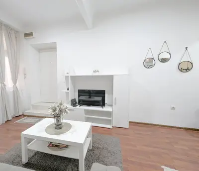 a white living room with a table and a fireplace at Central Peaceful Nest Belgrade in Belgrade