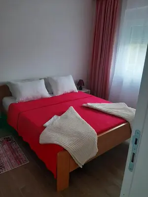 a bedroom with a bed with a red blanket at Apartman Jass in Stari Banovci