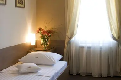 a bedroom with two beds and a window with a vase of flowers at Hotel Knezevina in Vranić